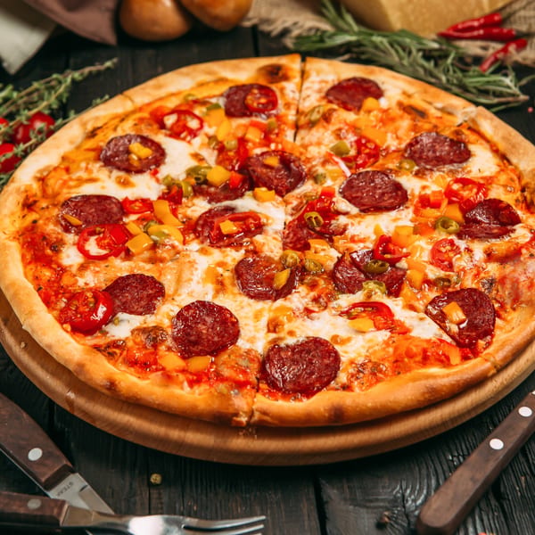 Saylor Mick's pepperoni pizza with bell peppers and cheese on a wooden board.