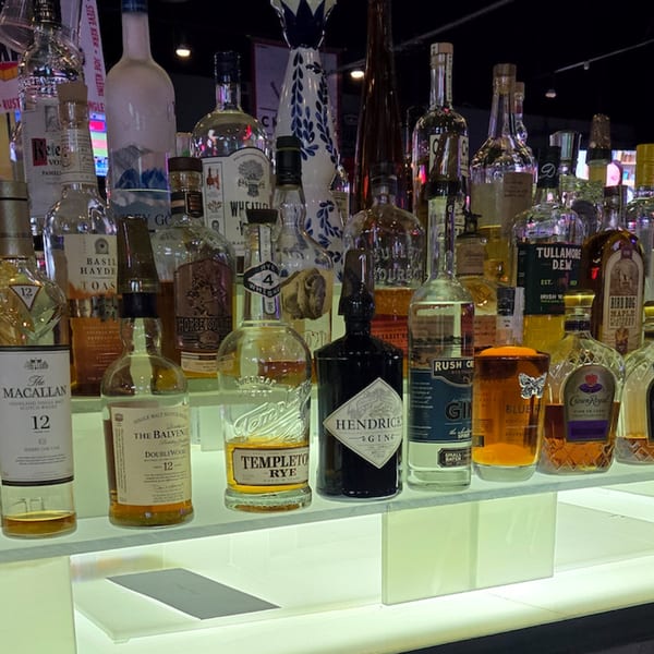 A well-stocked bar shelf at Saylor Mick's Pizza & Pub, featuring various liquor bottles.