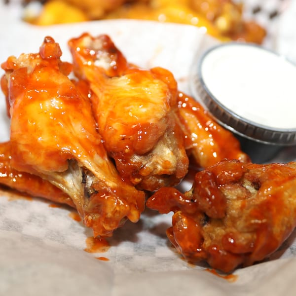 Saylor Mick's Pizza & Pub's buffalo wings coated in sauce, with a side of ranch dressing.